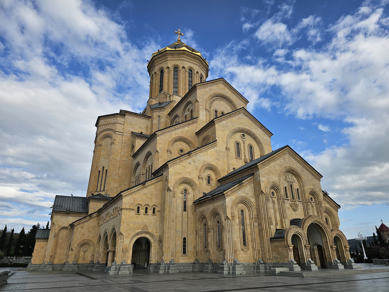 Holy Trinity Cathedral in Tbilisi, Georgia, seen from the plaza under a cloudy sky.