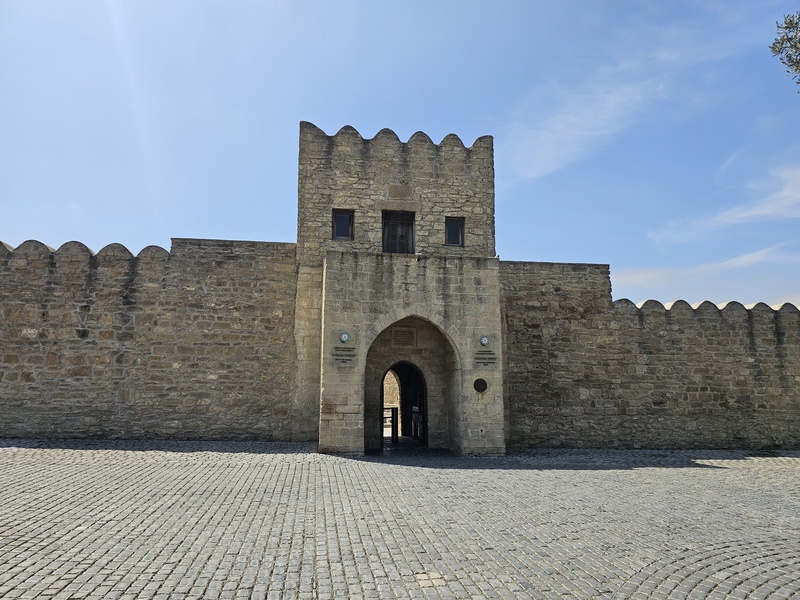 Atashgah Zoroastrian Fire Temple gate with arched entrance and crenellated walls under a clear blue sky
