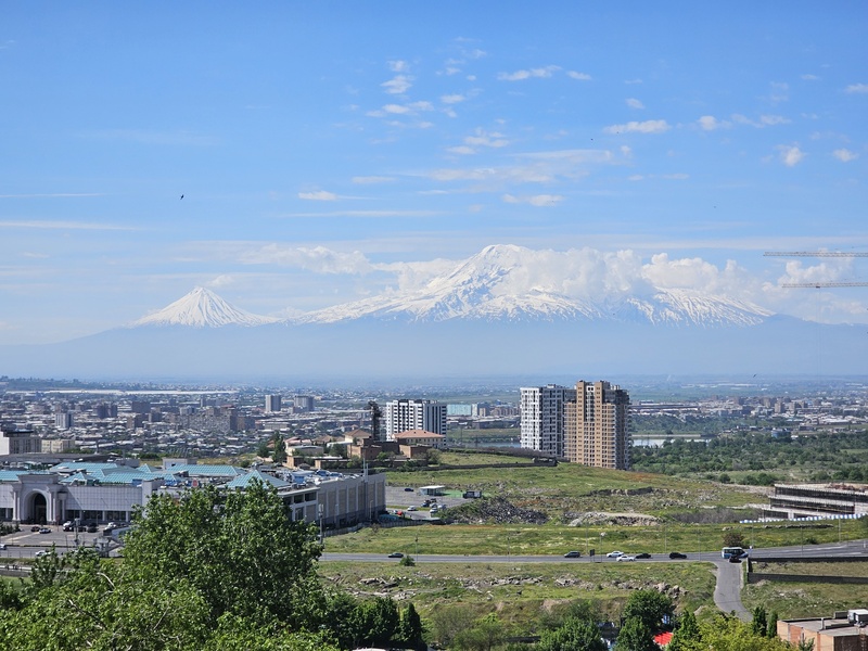 A panoramic view of Yerevan, Armenia, with the snow-capped Mount Ararat in the background under a clear blue sky.