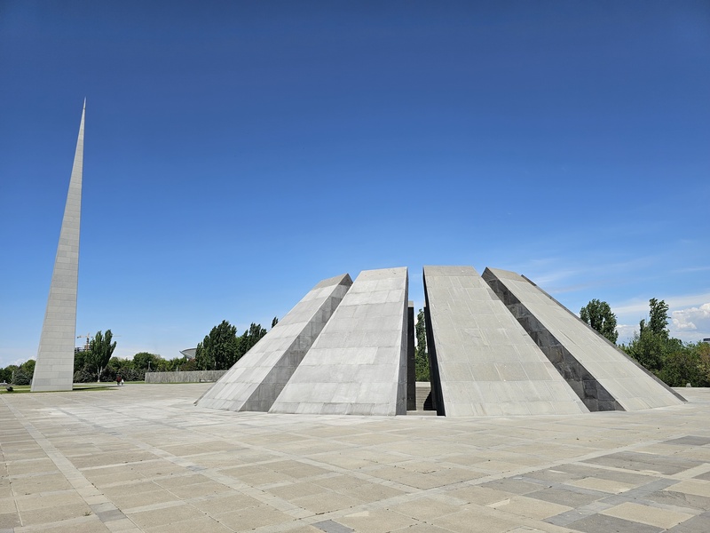 The Armenian Genocide Memorial in Yerevan, featuring a tall obelisk and large geometric stone structures against a clear blue sky.