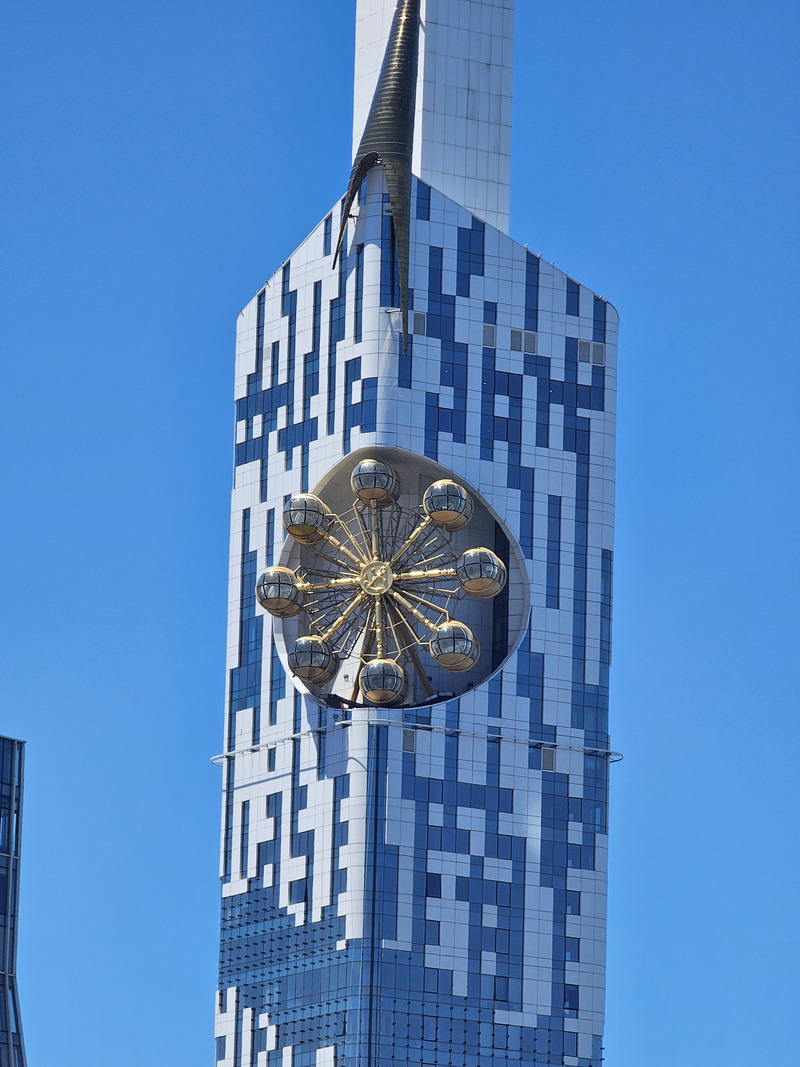 Batumi Tower with its golden Ferris wheel against a clear blue sky.