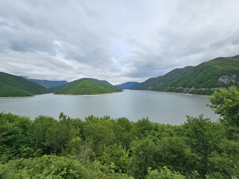 Green mountains around Zhinvali Reservoir under a cloudy sky in Georgia.
