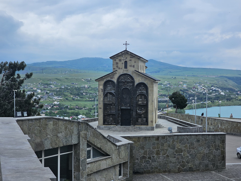 Church beside the Chronicle of Georgia overlooking Tbilisi Sea and green hills.